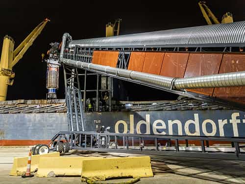 TeleStacker® Conveyor loading ship with wood pellets during nighttime port operation