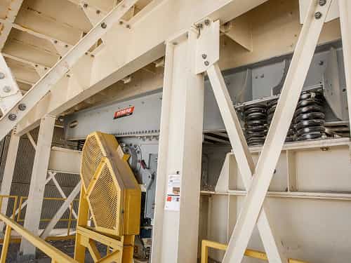 Intrepid® Vibrating Grizzly Feeder installed on stationary platform showing coil springs, guards, and steel bracing